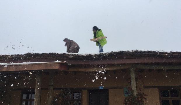 Sanatçılar kerpiç evlerin toprak damında kar küredi