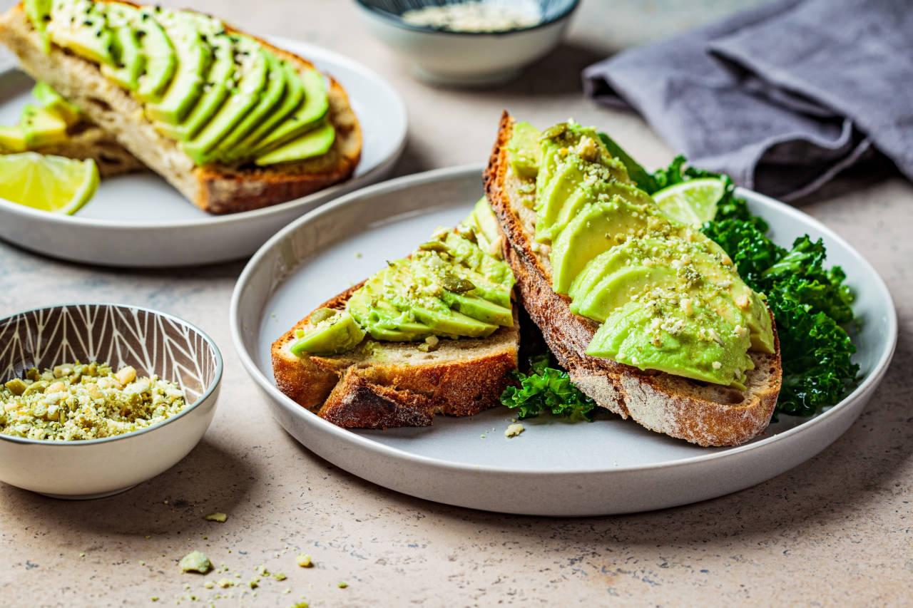 Avokado ezmesi üzerine dilimlenmiş avokado bulunan ekmek dilimleri