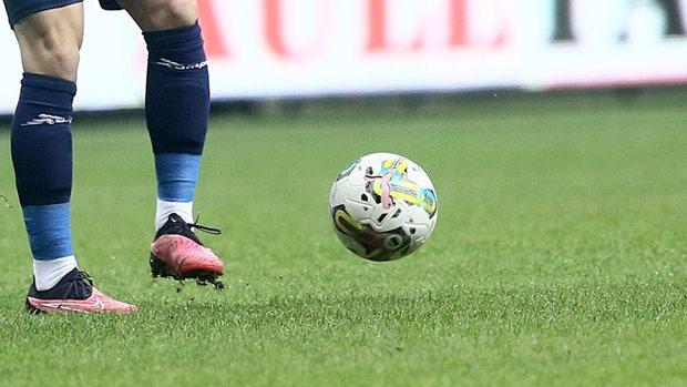 Futbol sahasında bir futbol topu ve arka planda bir oyuncu