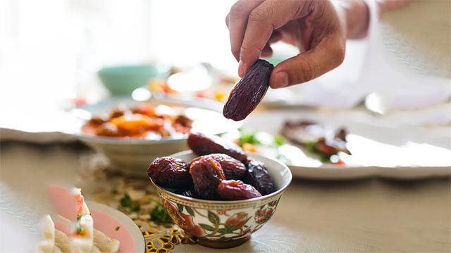 Orucunu açmak için, iftar sofrasından bir adet hurma alan bir kişi