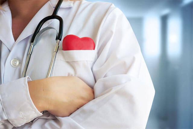 Kollarını birbirine bağlamış, boynunda stetoskop ve cebinde kalp figürü olan bir doktor
