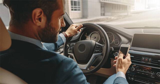 Araba kullanırken telefon ile ilgilenen bir adam