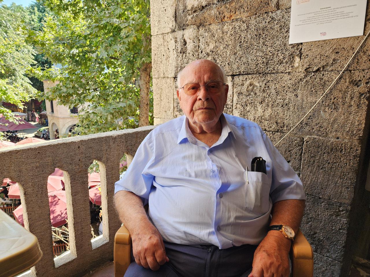 Halil Celbiş, Koza Han'da bulunan dükkânının önünde oturuyor.
