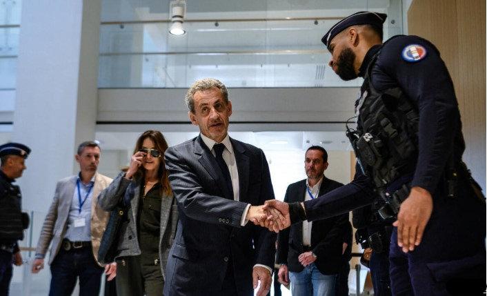 Sarkozy, dava günü bir Fransız polisiyle el sıkışıyor