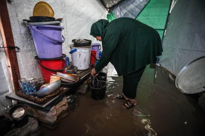 Filistinli kadın su dolan çadırını tahliye ediyor