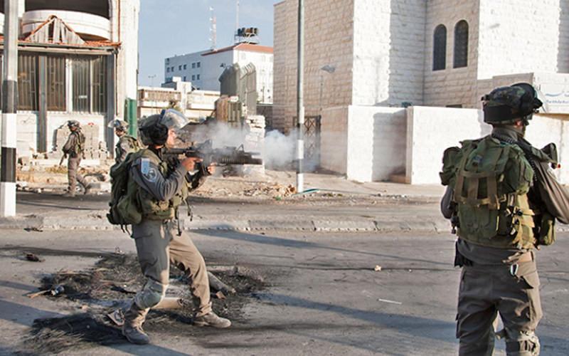 Resimde bir sokakta silah doğrultan İsrailli askerler görülüyor.