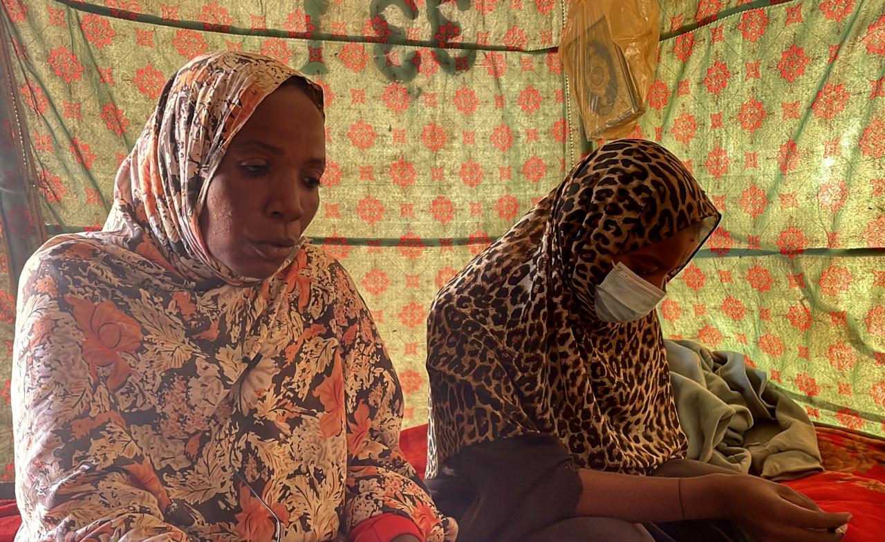 Sudan’ın Faşir kentinde Hızlı Destek Kuvvetleri’nin (HDK) saldırısında top mermisinin isabet etmesi sonucu kolunu kaybeden Suzi Musa (sağda), AA muhabirine açıklamada bulundu. Musa, Kuzey eyaletinin ed-Debbe şehrinde temel ihtiyaçların güçlükle karşılandığı el-Affad Mülteci Kampı’nda annesi Hatice Harun Sebil (solda) ile derme çatma bir çadırda yaşam mücadelesi veriyor.