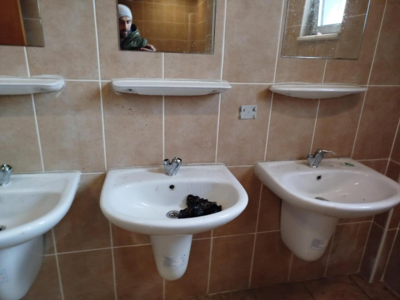 Siyah bir poşetin atıldığı bir lavabodaki tüm muslukların yerinden söküldüğü görülüyor.