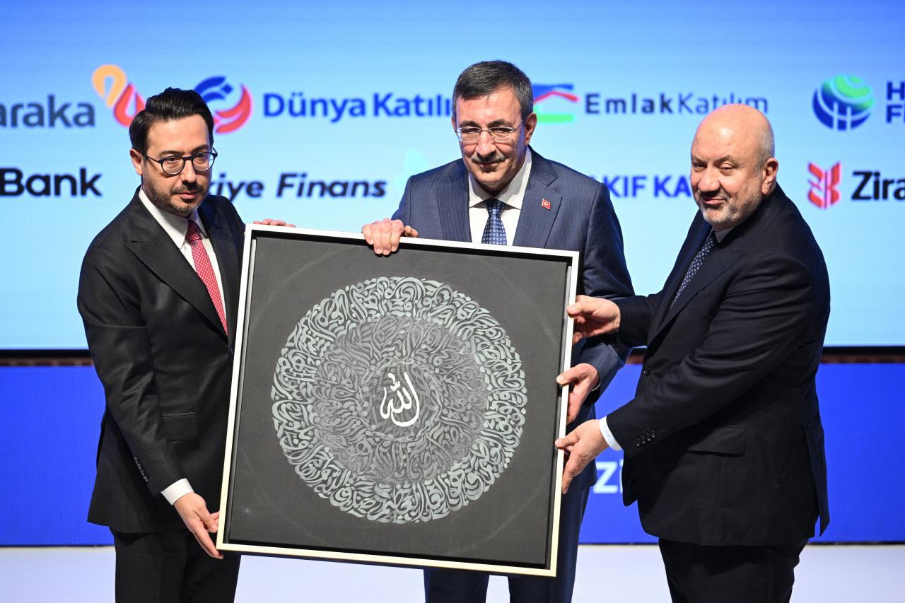  Anadolu Ajansı (AA) Yönetim Kurulu Başkanı ve Genel Müdürü Serdar Karagöz (solda), Türkiye Katılım Bankaları Birliği Başkanı Mehmet Ali Akben (sağda), zirveye katılan Cumhurbaşkanı Yardımcısı Cevdet Yılmaz'a (ortada) hediye takdim etti.