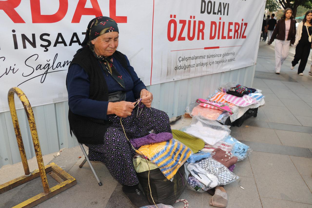 Sivas’ta kaldırım üzerindeki tezgâhında örgü ören Koç, hem üretim yapıyor hem de hazırladığı ürünleri müşterilerine ulaştırıyor.