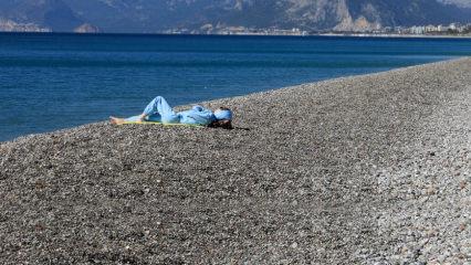 Konyaaltı Sahili'nde eşofmanlarıyla güneşlenen turist
