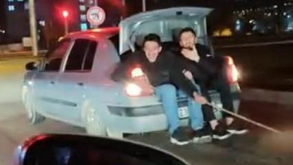 Bagaja oturup arızalanan arabayı elleriyle tuttukları iple &ccedil;ektiler