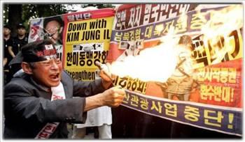 Güney Korenin başkenti Seulde 9 Ekim 2008de çekilen bu fotoğrafta bir protestocu Kuzey Kore lideri Kim Jong Ilin bir posterini yakıyor. Kuzey Kore hükümeti protestonun yaşandığı gün erken saatlerde ilk nükleer denemesini yaptığını açıkladı. 25 Masyı 2009da Güney Koreliler ve uluslararası kamuoyu Pyongyangın yer altında yaptığı ikinci testi de başarıyla sonuçlandırdığını açıklaması üzerine çok öfkelendi. Bu ikinci silahın gücünün İkinci Dünya Savaşının sonunda Hiroşimayı yerle bir eden bombaya denk olduğu söyleniyordu.