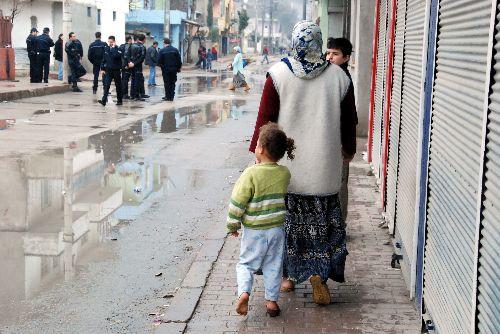 Hava yağmurlu ve soğuk, yerler ıslak ama ismi bile öğrenilemeyen minik kız bir terliğini kaybettiğinin farkında bile değil. Bir kaç metre ötede ise yasadışı gösteri yapanlar ile polisler kapışmış durumda.