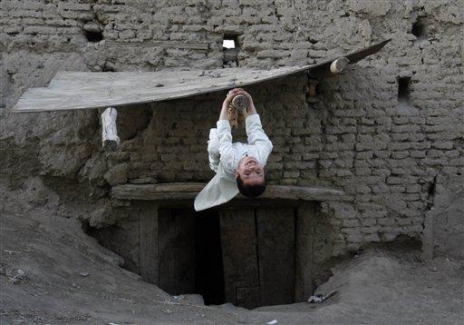 Bir oyuncağı bile yok ama o hâlâ gülebilecek kadar hayat dolu... Evlerinin kapı tentesindeki bir tomruk ona oyuncak olarak yetiyor ve artıyor bile... Çünkü Afganistan'da da yaşıyor olsa o bir çocuk... 
<br><br>Foto: Ahmad Nazar - AP