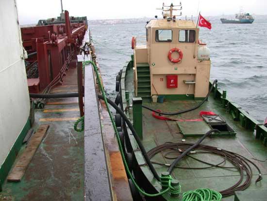 Tankerde yüklü olan akaryakıt hortumlarla karaya taşınmak üzere aktarma tankerine çekiliyor