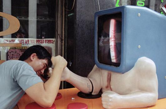 <strong>13. Bileğinize kuvvet...</strong><br><br>
1991 -> Güney Kore sokaklarının 1991 yılında özel bir konuğu vardı. Şekli itibariyle insanımsıdan çok ekranımsı olarak niteleyebileceğimiz bu robot, bilek güreşi sevenlerin dışında kol kaslarını güçlendirmek isteyenler için de eğlenceli bir seçenekti.