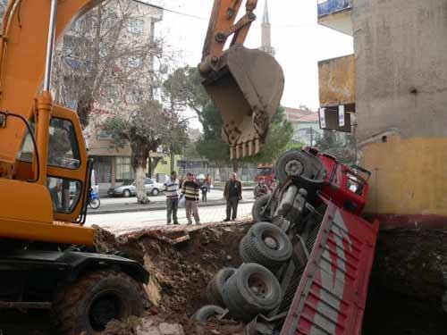 Manisanın Turgutlu ilçesinde bir inşaat firmasına ait kamyon bina temeli için kazılan çukura düştü