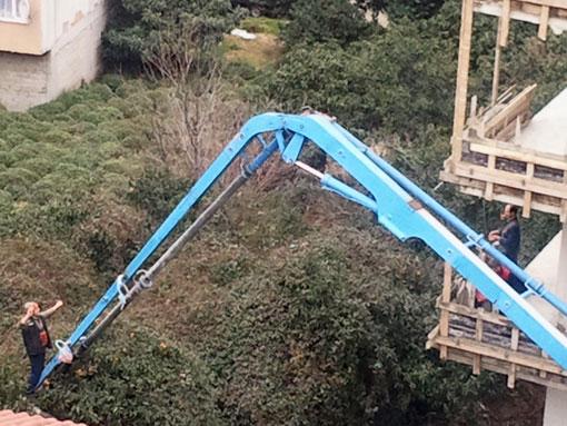 Beton dökümü için gelen tankerin uzun vincine asılarak ağaçlara kuş gibi konan iki işçi, ağacın üst bölümünde kalmış mandalinaları toplayarak arkadaşlarına attı.