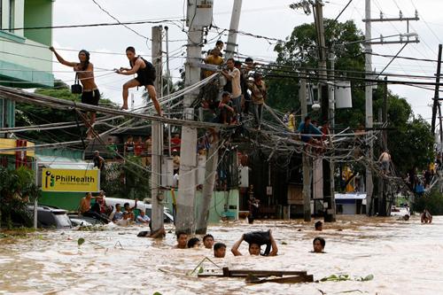 Filipinleri vuran tayfun kasırgası sonucu mağdur olan vatandaşların kimi hayatta kalabilmek için elektrik tellerinin üzerinden yürüyerek kaçmayı seçti. Kimileri ise 27 Eylül 2009 tarihini geride bırakabilmek için, boğazına kadar gmüldüğü sel suları ile mücadele yolunu seçti. (REUTERS/Erik de Castro)