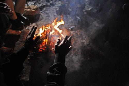 ELAZIĞ DEPREMİNDE SOĞUK HAVADA GECEYİ DIŞARIDA GEÇİRMEK ZORUNDA KALAN BİR YAŞLI ADAM, KÖY MEYDANINDA YAKILAN ATEŞİN ÖNÜNDE ISINMAYA ÇALIŞIYOR. FOTOĞRAF: ABDULLAH COŞKUN