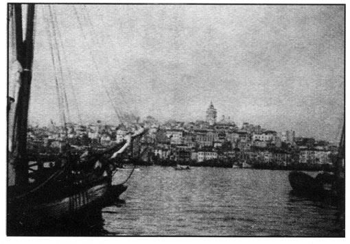 <b>2 Ekim</b><br><br>
Dönen dervişler. Onlan kayıp dergâhlarında ziyaret etmek ve insan kaynayan Galata Köprüsünün üzerinden yürüyüp İstanbul'a geçmek istiyorum. Öğleden sonra saat üç. Bir zamanlar Bizans'a ait olan şehrin bu uzayıp giden kısmının üzerine doğrudan güneş vuruyor. Güçlü güneş ışıklan, çatı tepelerinin altın siluetlerine, haşmetli kubbeler ve minarelere altuni bir arka fon veriyor, aynen eski Bizans resimlerinde olduğu gibi.
Artistik bir dökme demir ızgara dergâhı çevrelemekte. Dar geçitten geçerek avluya çıkıyorsunuz ve daha sonra uzun bir duvar boyunca taş bir patikadan yürümeye devam ediyorsunuz. Kınk bir pervazdan içeri göz attım, loş ışıkta uzun bir taş sanduka dizisi seçebildim. Burada şeyhler yani kurucular yüzyıllardır yatmakta. Arkadaki taş sanduka sadece daha düz,
165 ufalanan taş blokları, silinmiş kitabeler ve unutulmuş isimler.
Dergâh caminin içi sekizgen bir tasarıma sahip, havası serin, Kuran'dan ayetlerin olduğu yuvarlak levhalar duvara asılı, arkada yüksek kandillerden ışıklar yayılıyor. Bütün alan aşağıda yer alan ahşap bir kafesle ikiye ayrılmış. Daha büyük olan kısım biraz yüksekte olup ince açık kahverengi devetüyü bir halıyla kaplı, daha küçük olan alan ise ziyaretçilere ayrılmış. Kandillerin altında oldukça uzaktaki bir köşede dervişler bir kilimin üstüne sıkı bir halka oluşturacak şekilde besbelli şeyhleri olan uzun sakallı yaşlıca birinin etrafına çömelmişler. Hepsi siyah cübbelere bürünmüş ve oldukça uzun kahverengi fesler giymişler. Ayaklan çıplak. Yumuşak bir şekilde zikir ediyorlar, görünmeden ve kesintisiz bir şekilde, yakındaki bir odadan monoton bir ney ve kanundan melodi yayılıyor. İlk başta sanki çok uzak bir yerden geliyormuş gibi geliyor, daha sonra musiki yavaşça yükseliyor, yaklaşıyor, artıyor, yine de sürekli olarak sükûnetini koruyan düzgün ve düzenli yekpare bir bütünlüğe ulaşıyor. Aniden hepsi ayaklanıyor, cübbelerini fırlatıyor, uzun hafif entarilerle ve kısa gömleklerle kalıyorlar. Yaşlı olan ileri doğru adım atıyor, diğer dervişler onu aynen takip ediyorlar ve odanın etrafını üç defa tavaf ediyorlar.