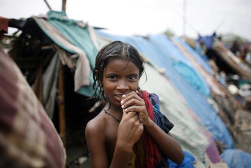 2 Haziran 2009 tarihinde meydana gelen med-cezir hareketlerinin neden olduğu Aila Kasırgası, geçici olarak temin ettikleri çadırın önünde poz veren bu kız gibi, Bangladeşin güneybatısında yaşayan birçok insanı da evinden etti. (REUTERS/Andrew Biraj)