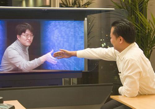 <p><strong><span style="color: #0000ff;">HOLOGRAFİK GÖRÜNTÜ SANDALYENİZDE OTURACAK<br /></span></strong><br />Ofise varıyorsunuz. Girişte plastik güvenlik kartı kullanmıyorsunuz. Kimliğiniz bedeniniz. İş arkadaşlarınız toplantıya yetişemese de sorun yok. Holografik görüntüleri sandalyeleri dolduruyor.<br /><br />Sizi ofise getiren krizin sebebi de duvarlardaki çatlak. Robotlar duvarı tamir edemediği gibi çatlağa zarar da veriyorlar. Duvarların tamiri için insan müdahalesi gerekiyor. Dolayısıyla her hareketinizi algılayan kuantum robotları başka bir merkezdeki insanlarla tek beden oluyor. Avatar filmini hatırlayın.</p>