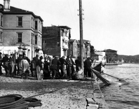 <p><strong><span style="color: #0000ff;">BEBEK’TEN AĞ ÇEKMEK <br /></span></strong>Dizi dizi yalılarıyla Bebek kıyıları. 1930’lu yıllardaki bu fotoğrafta, bugünün balıkçı lokantalarının yerinde o zamanlarda da yine balıkçılar var. Ama büyük farkla, Boğaz’dan ağ dolusu balık çeken balıkçılar.</p>